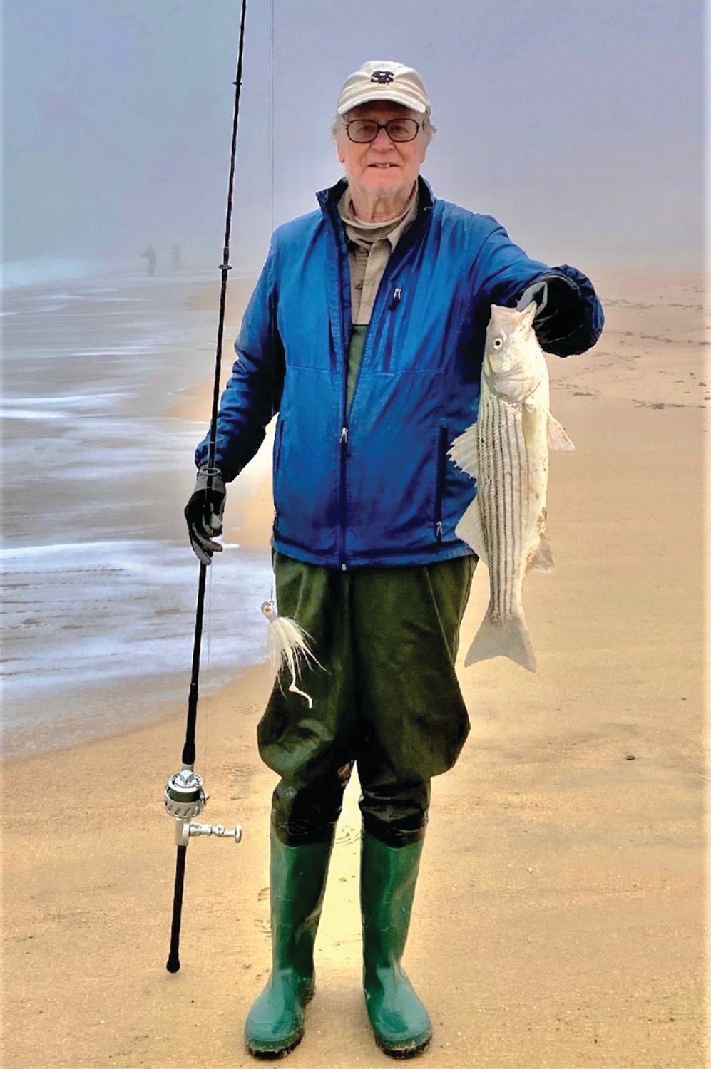 STRIPED BASS: Angler Gil Bell with a striped bass caught on a foggy South County beach.
